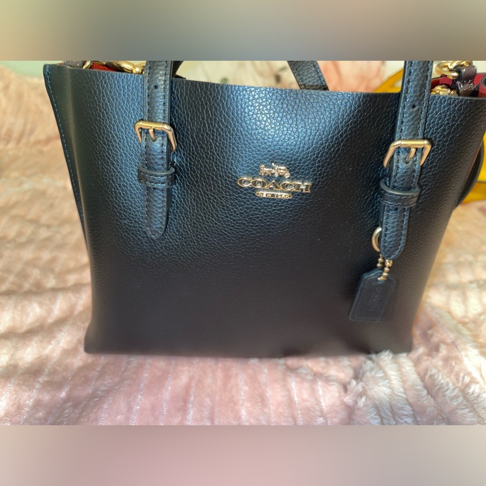 Small crossbody black Coach bag with gold details and burgundy inside